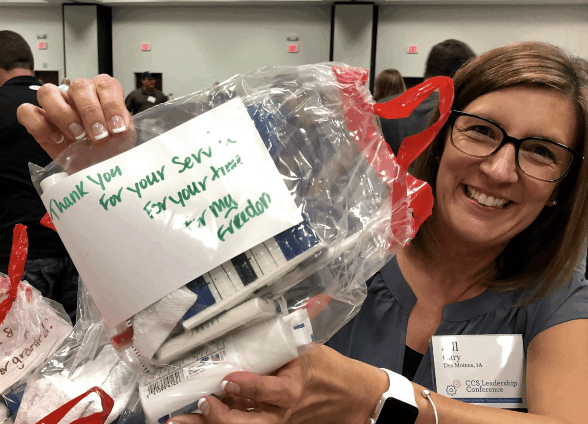 Women holding up hygiene kits for Veterans
