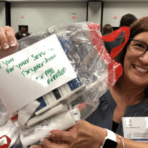 Women holding up hygiene kits for Veterans