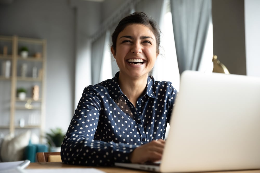 Cheerful girl smiling while on her laptop during virtual teambuilding event